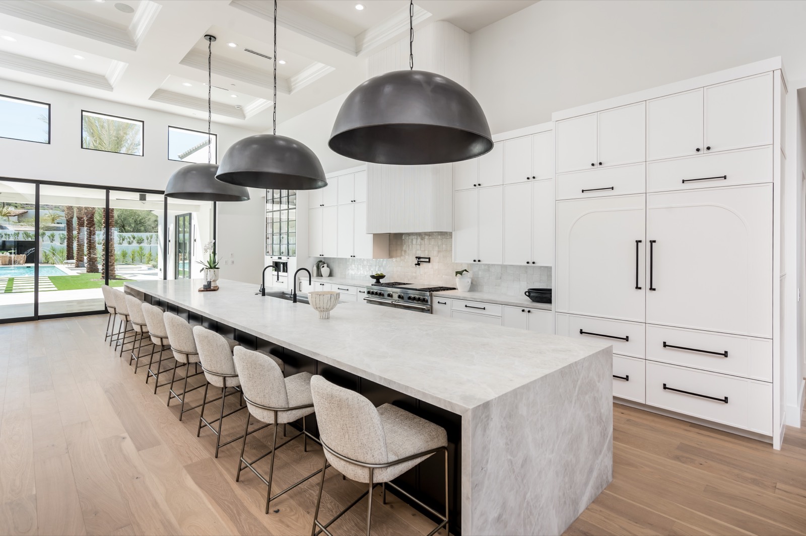Long white kitchen with a black island base and dome pendants