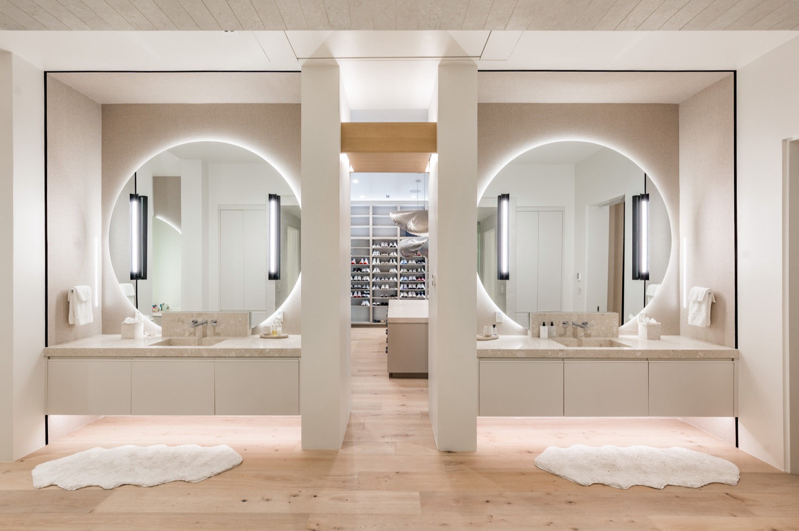 Twin floating vanities beneath large round mirrors