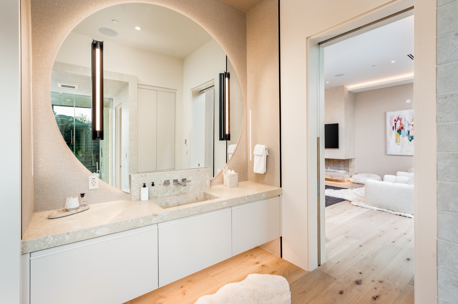 Primary bath vanity with a round mirror and wall sconce