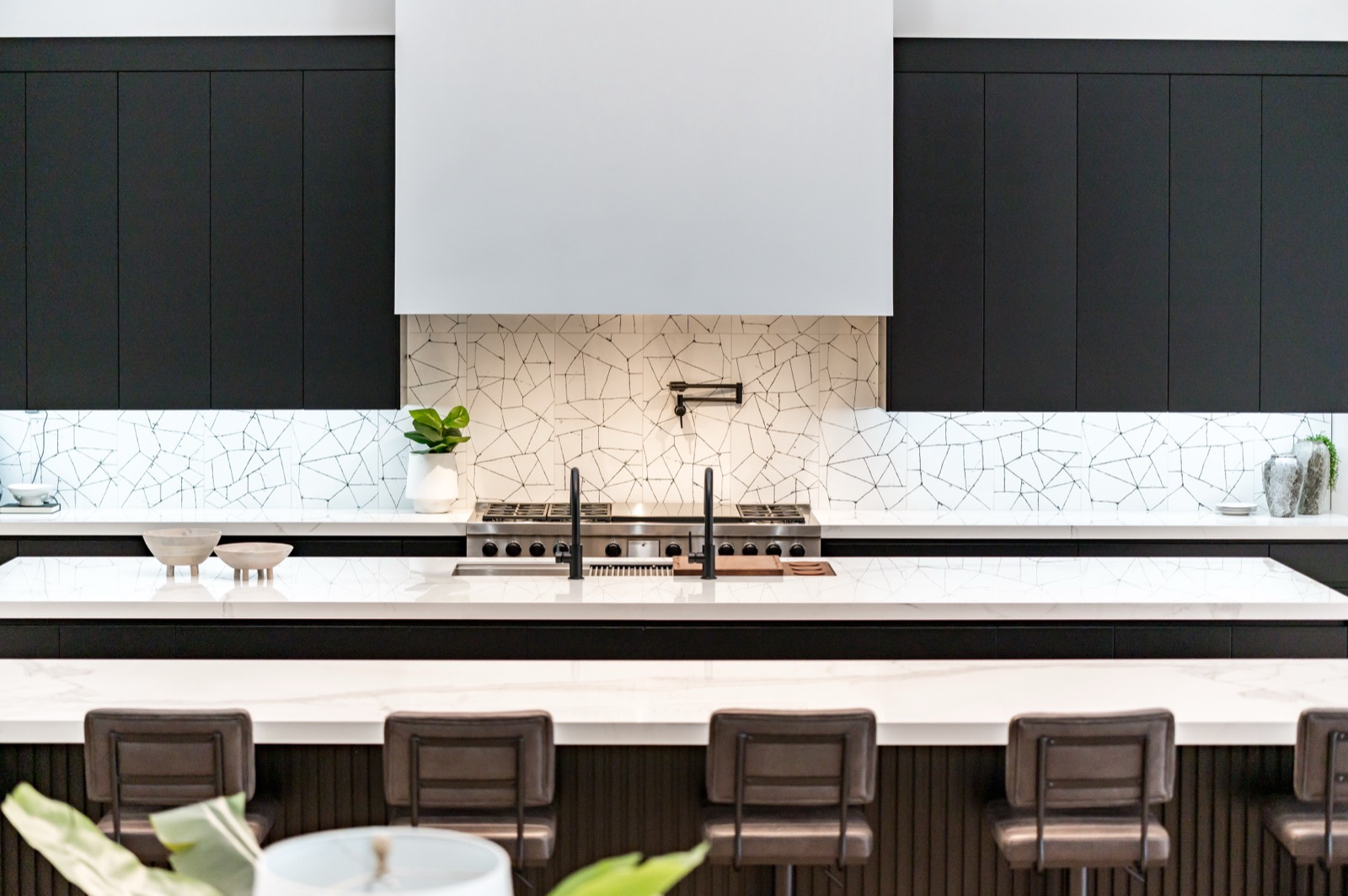 Matte black kitchen with a white plaster hood and marble island