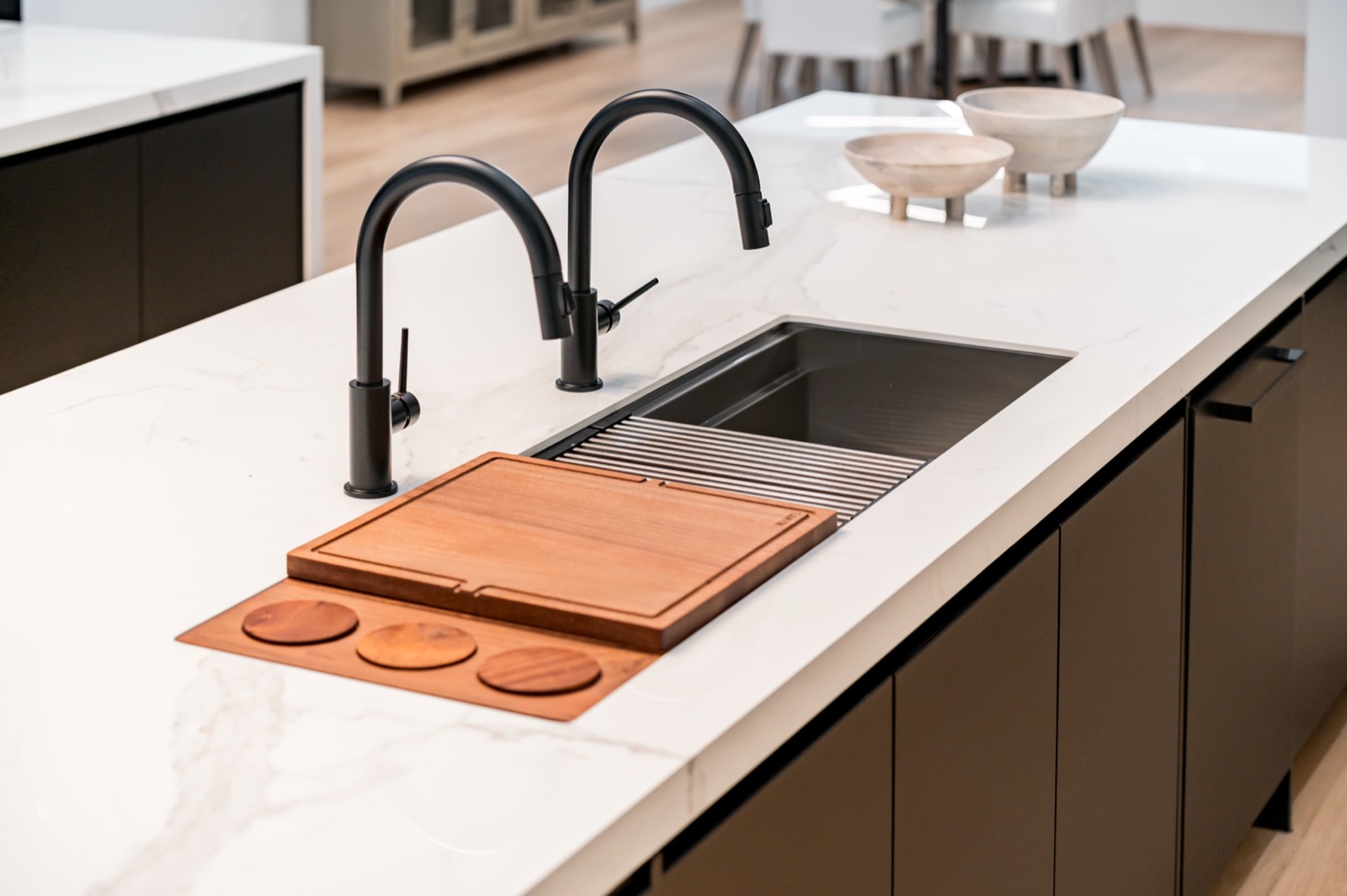 Island sink with black faucets and a wood cutting board