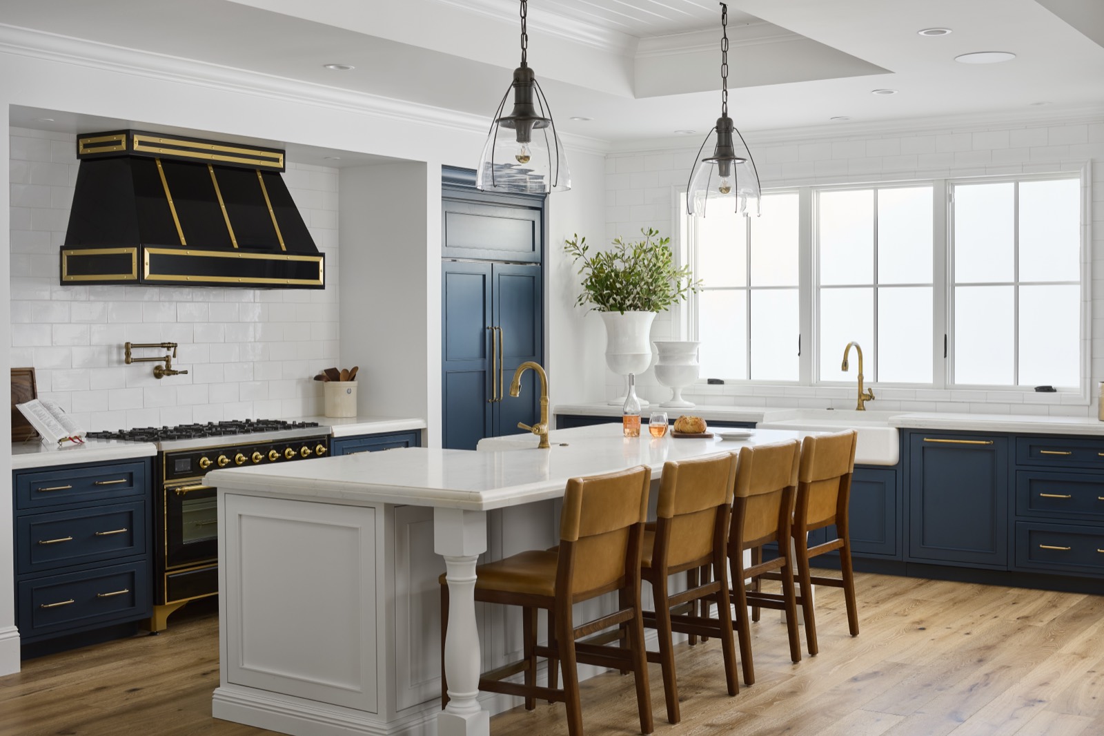 Navy and white kitchen with a black and brass hood and a furniture-style island