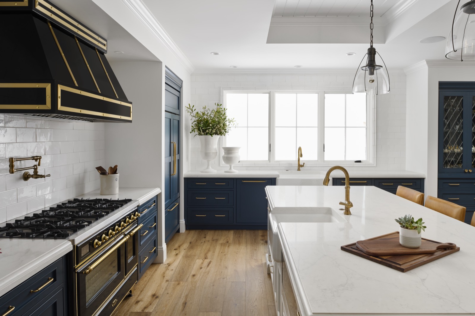 Navy range wall and brass faucet seen across a white island