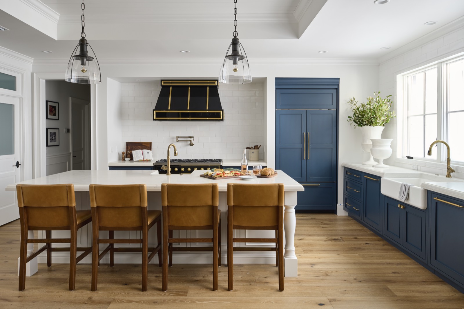 Kitchen with leather stools, a farmhouse sink and navy cabinetry