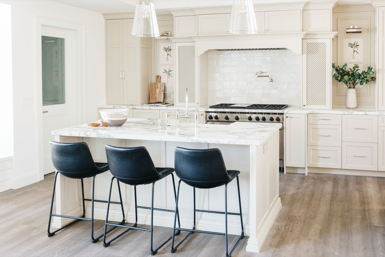 White kitchen with a marble island and navy stools