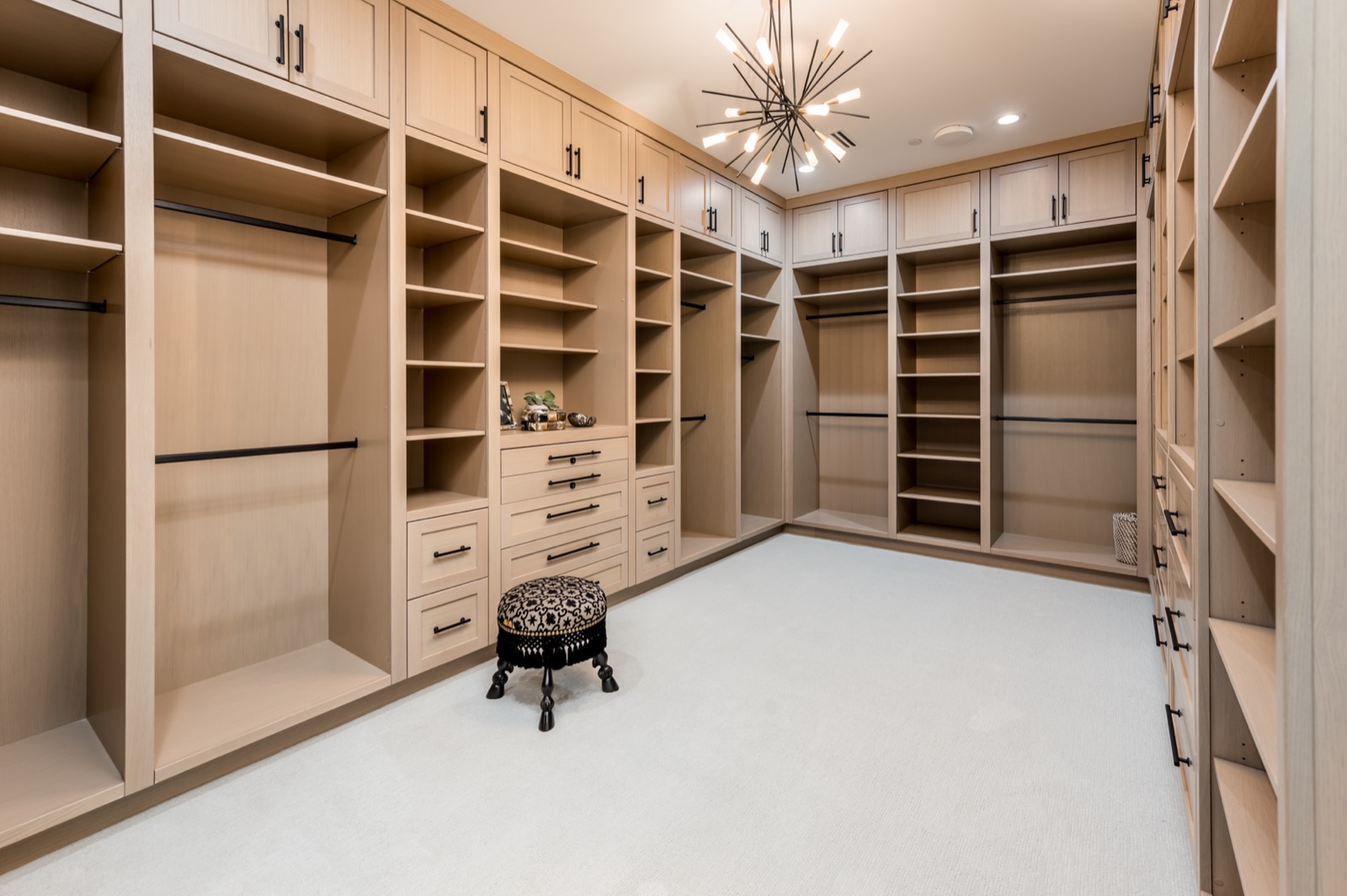 Oak dressing room with open hanging and shelving under a chandelier