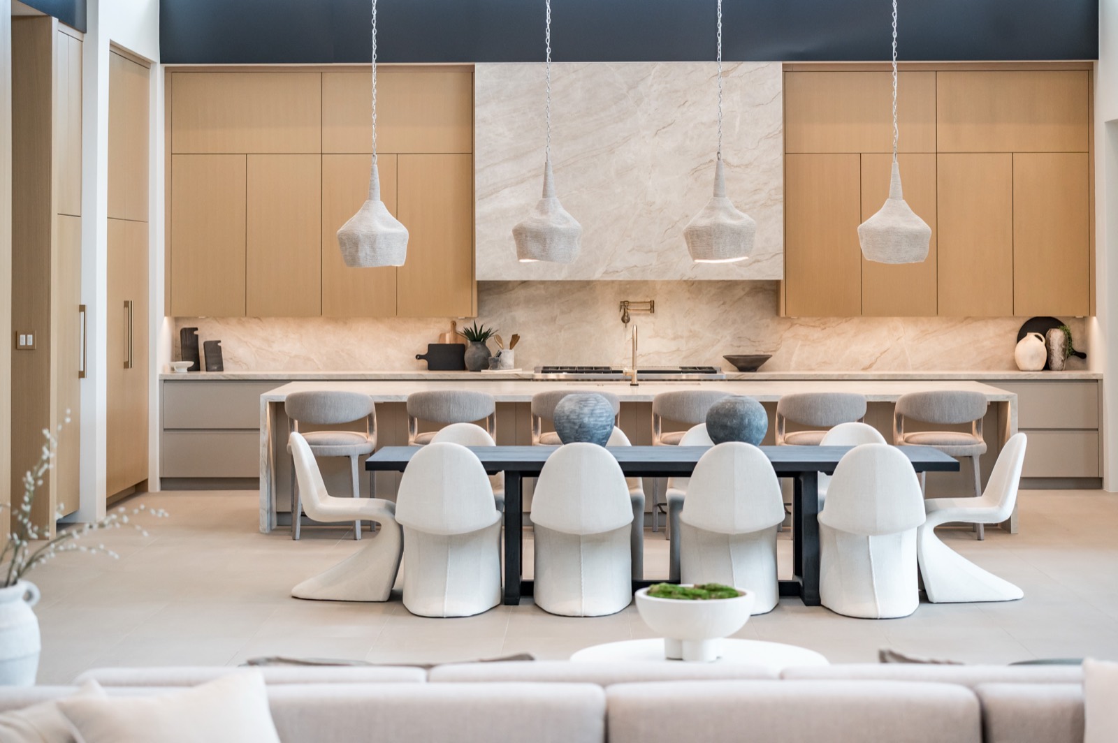 White oak kitchen wall and marble hood beyond a long dining table
