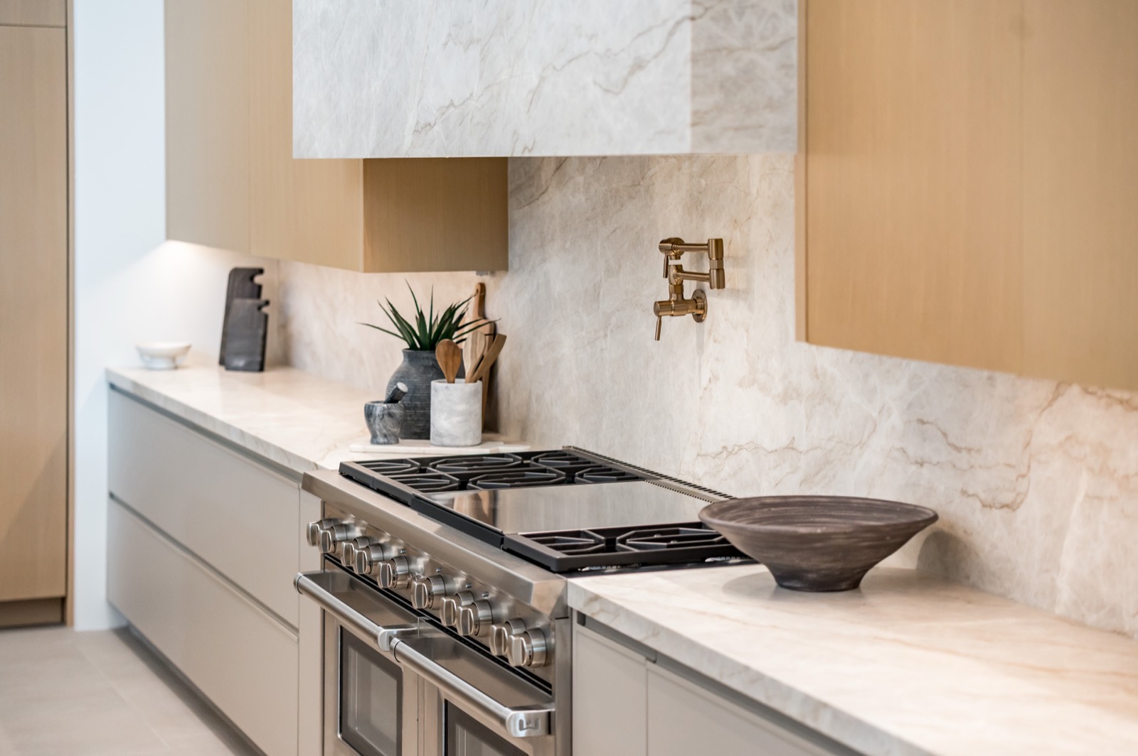 Range wall with white oak cabinetry and a marble backsplash