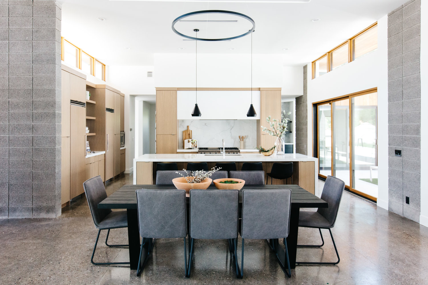 Open kitchen and dining room with a long oak island and oak wall
