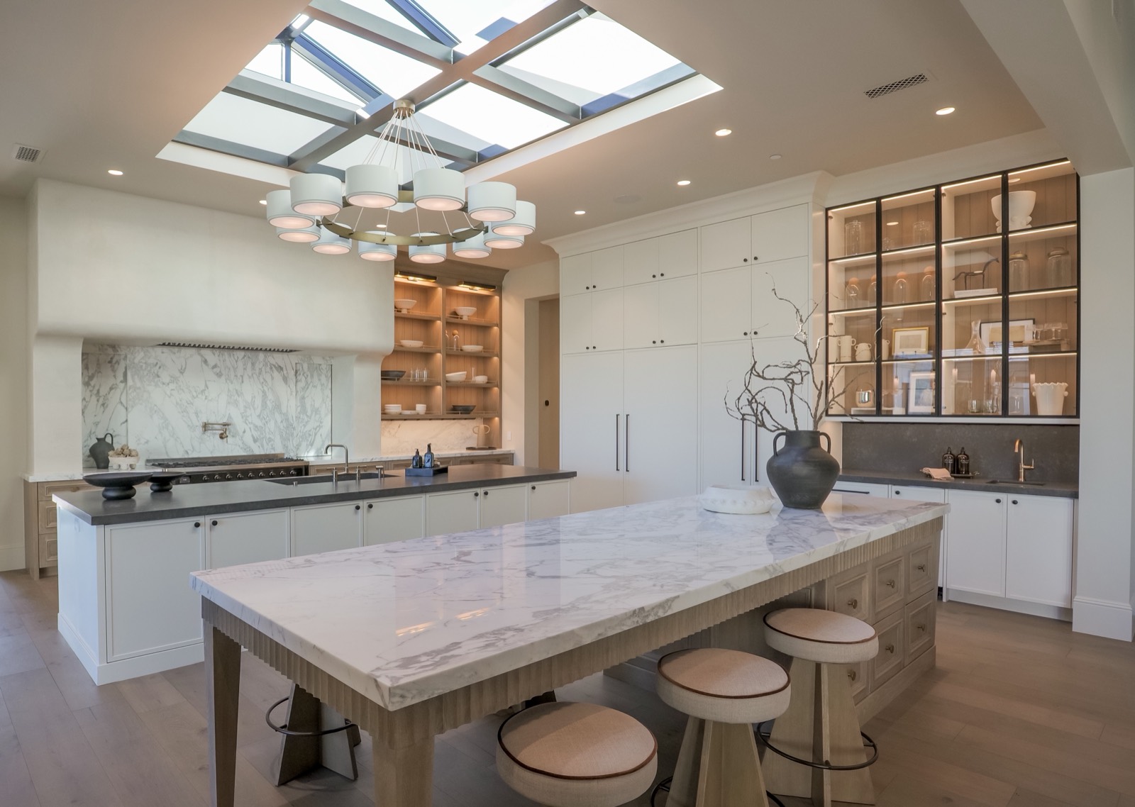 Kitchen under a coffered skylight with a marble island and glass-front cabinetry