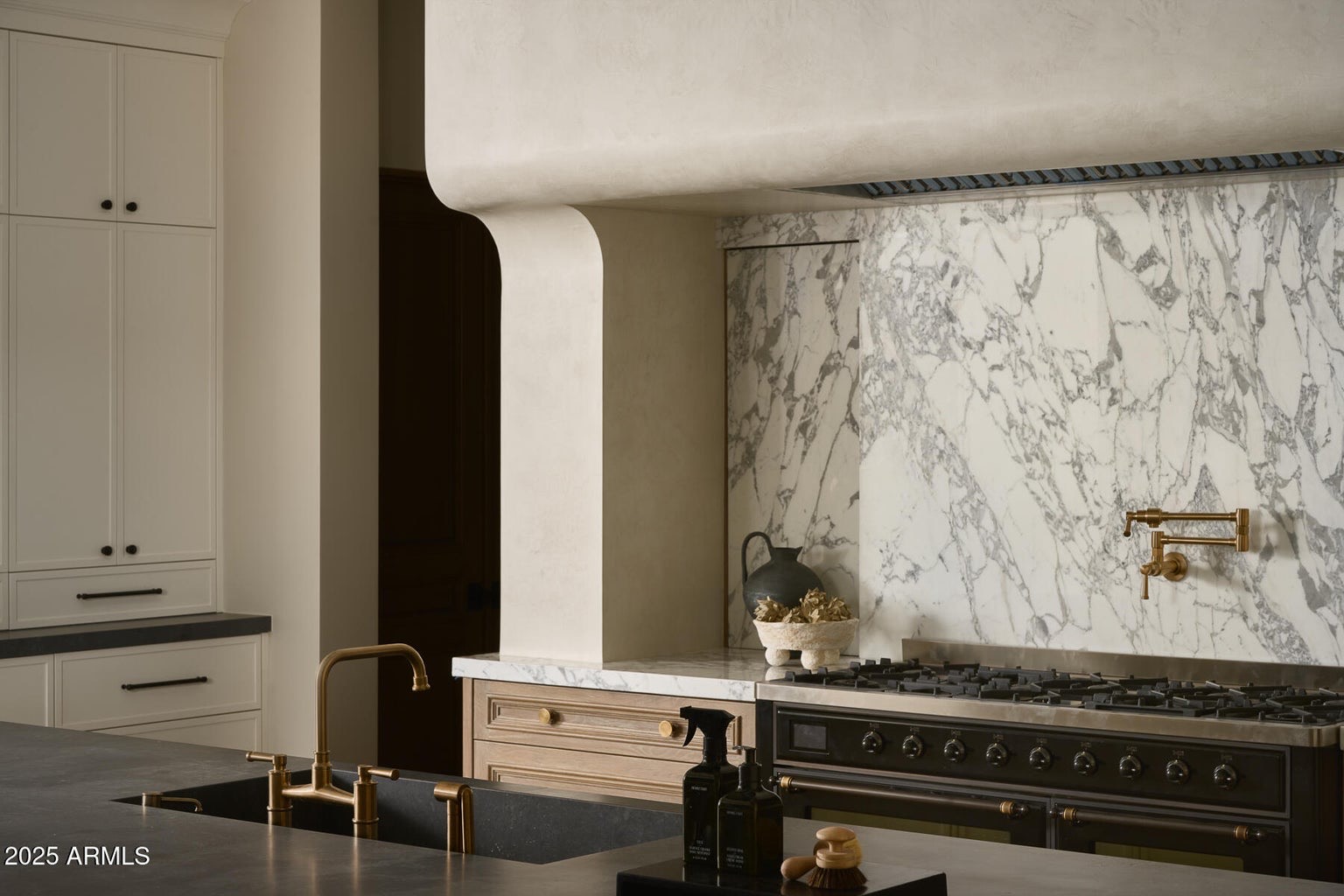 Curved plaster hood above a range, set against a full-height marble slab