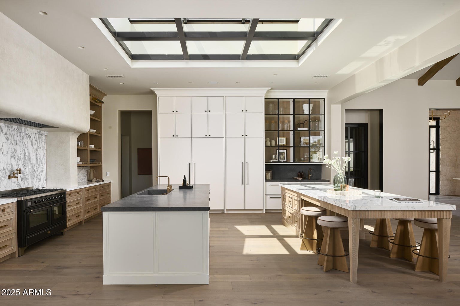 Wide view of the kitchen with tall painted cabinetry and an oak island
